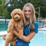 female concierge holds puppy goldendoodle outside