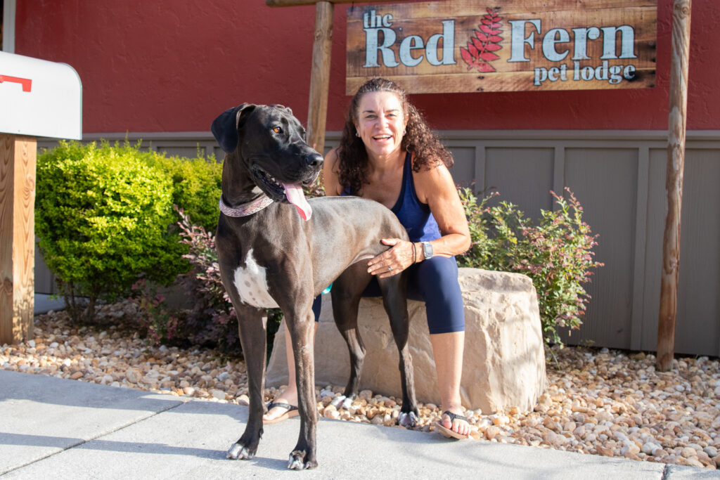 Customer hugging her great dane in front of red fern